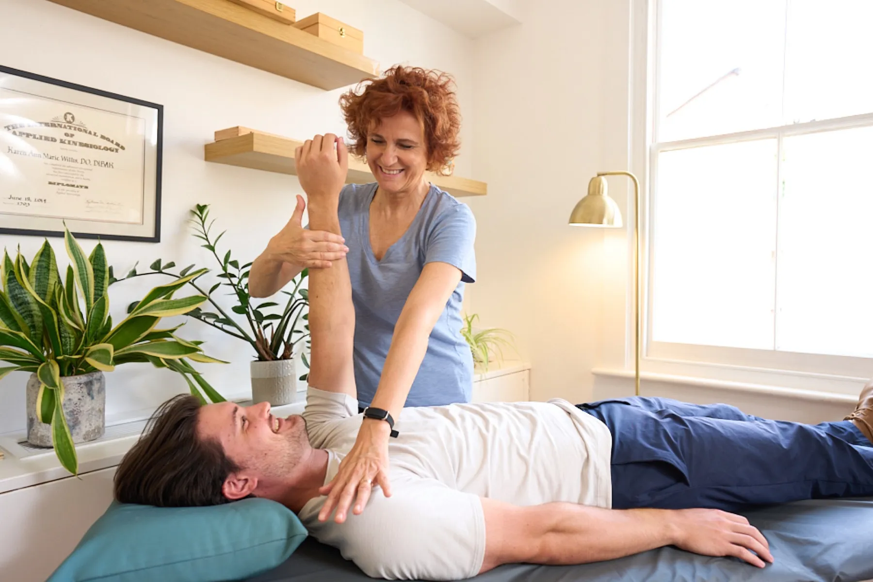 An ICAK practitioner performing a manual muscle test on a patient's arm during an Applied Kinesiology assessment