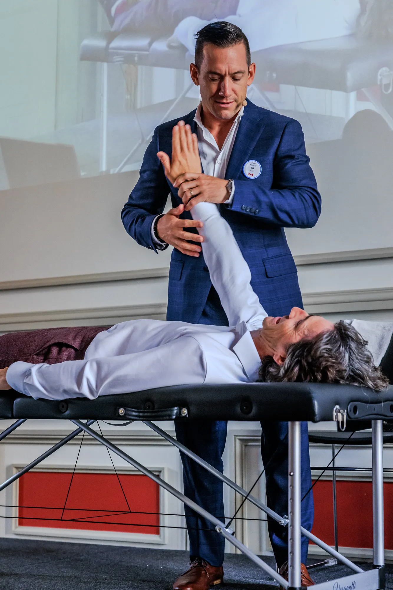 An ICAK practitioner performing a manual muscle test on a patient's arm during a seminar