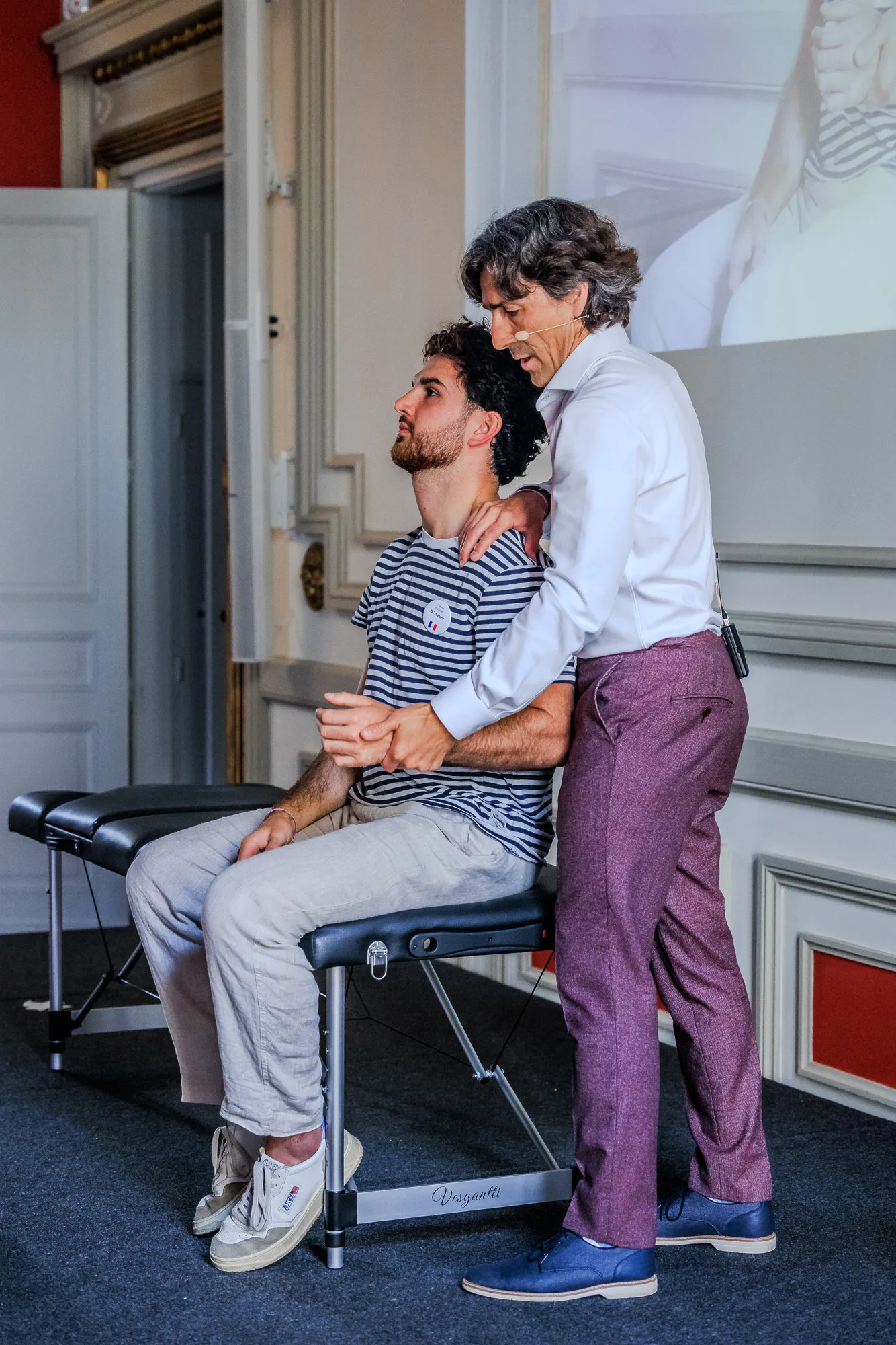 An ICAK practitioner working with a seated patient during hands-on instruction at a seminar